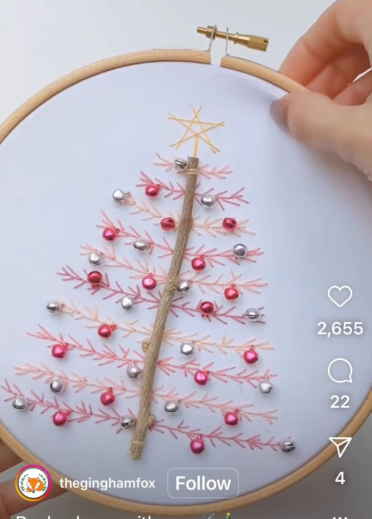 someone is stitching a small christmas tree on a white hoop with red and silver beads