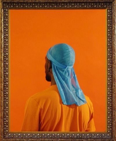 a man in an orange shirt is wearing a blue turban over his head