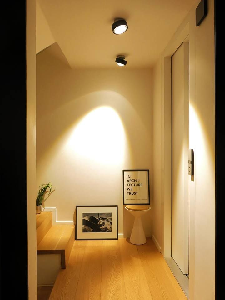 an empty hallway with light coming in from the ceiling and framed pictures on the wall