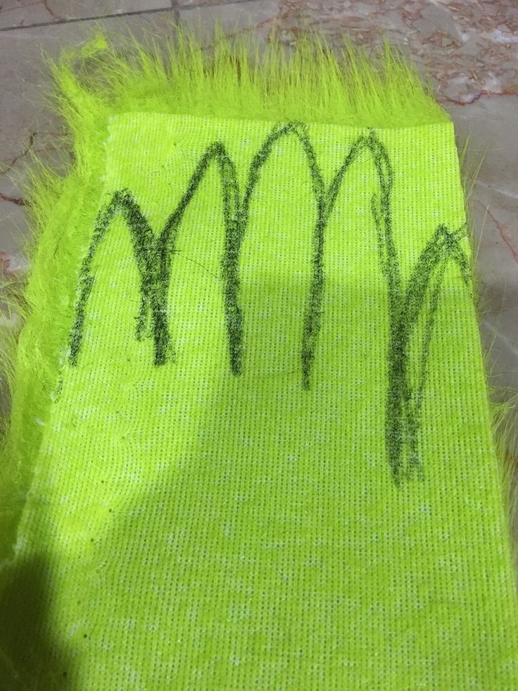 a piece of cloth with green grass on it and the word moo written in black ink