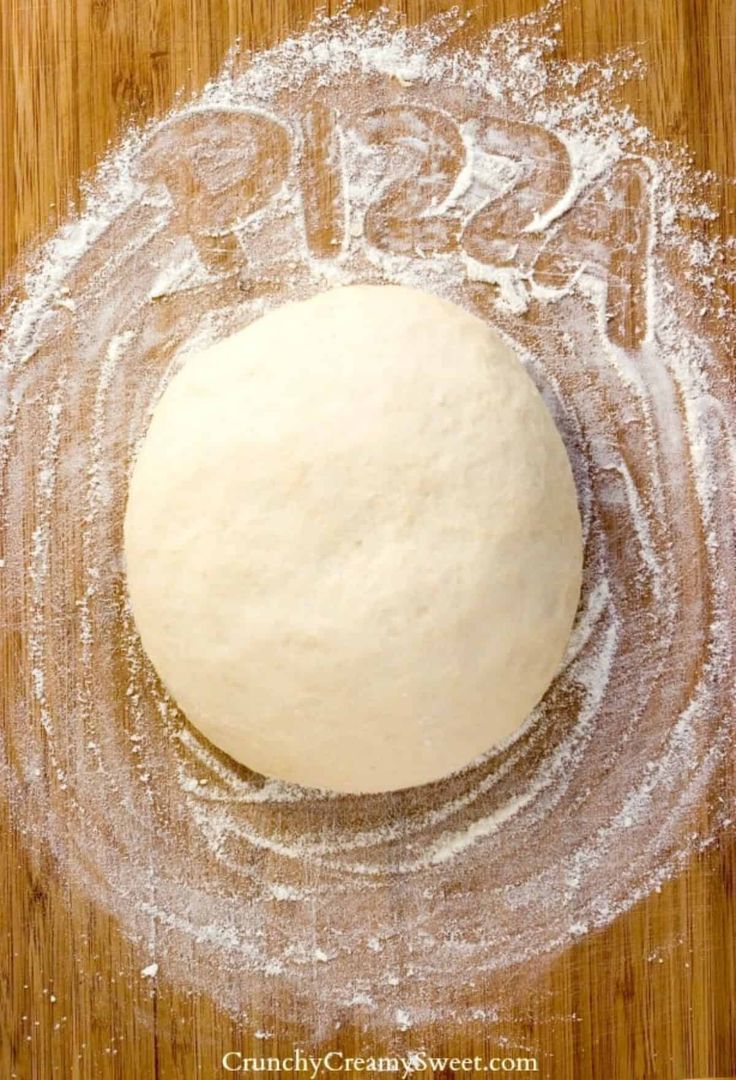 a round doughnut sitting on top of a wooden table covered in powdered sugar