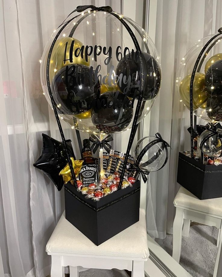 two clear vases filled with black and gold balloons sitting on top of a white table