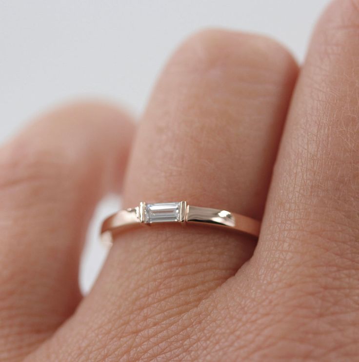 a woman's hand with a diamond ring on top of her finger, showing the band