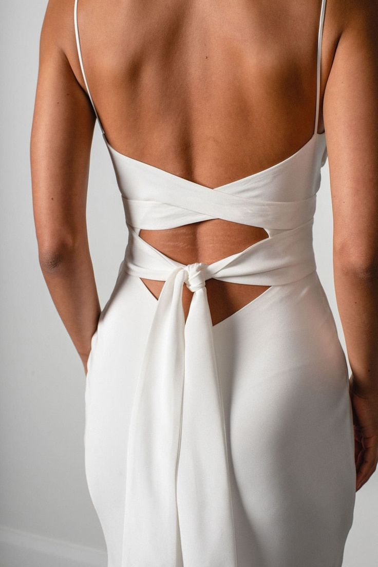 the back of a woman wearing a white dress with an open cutout on it