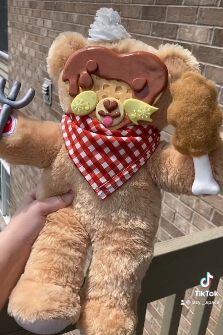 a teddy bear wearing a bandana and holding an object in it's hand