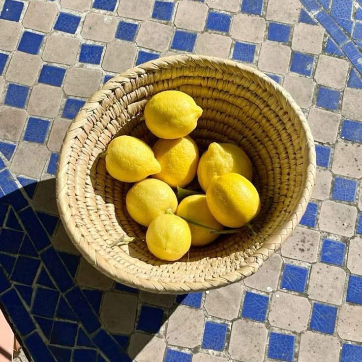 a basket filled with lemons sitting on top of a blue and white tile floor