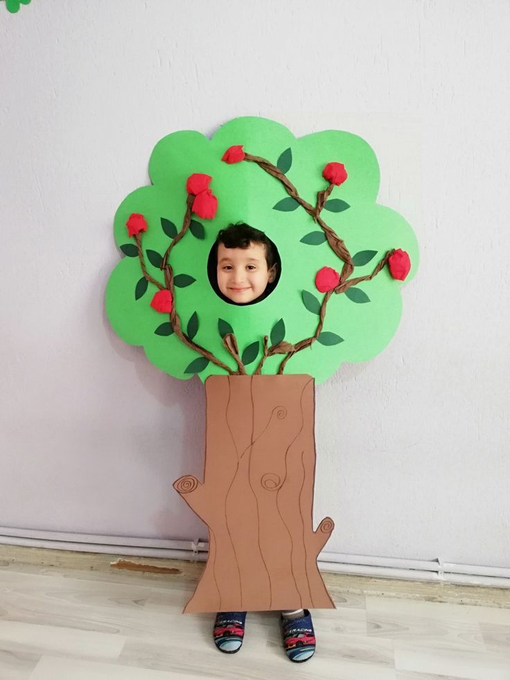 a young boy standing in front of a cardboard tree