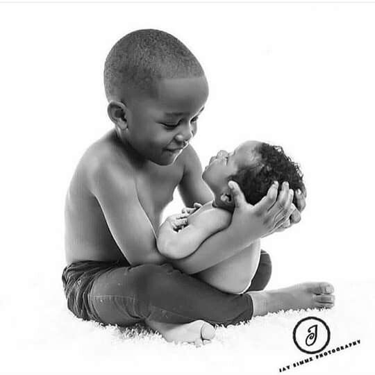 a black and white photo of a young boy holding a baby