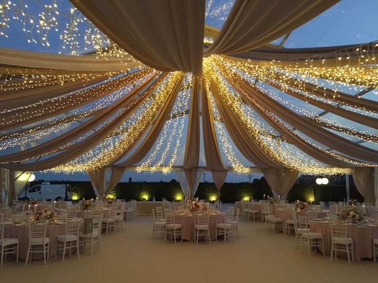 the inside of a tent with tables and chairs set up for a wedding or other function