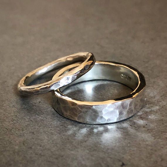 two wedding rings sitting on top of a gray counter next to each other, with one ring in the middle