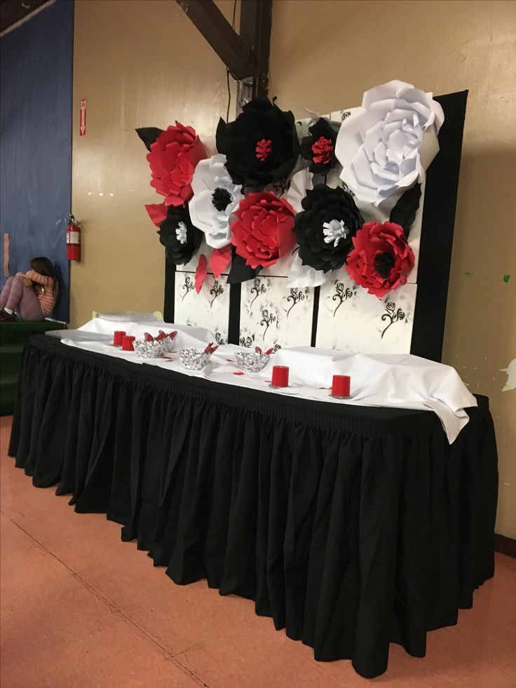 the table is set up with black, white and red paper flowers on top of it