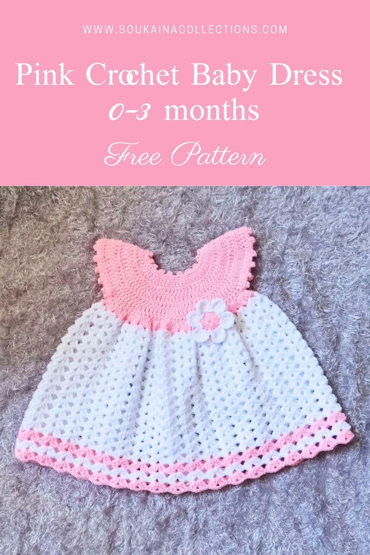 a pink and white crochet baby dress sitting on top of a gray blanket