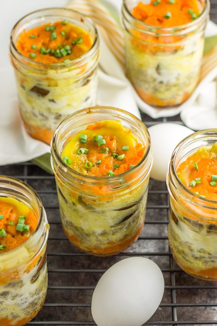 three jars filled with food sitting on top of a counter next to eggs and vegetables