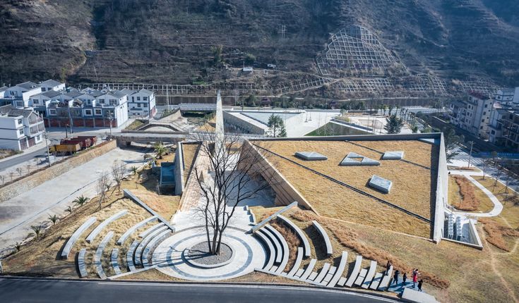 an aerial view of a building with stairs and trees in the foreground, surrounded by mountains