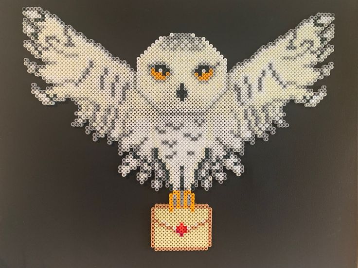 an owl made out of legos on a black background with yellow eyes and white wings