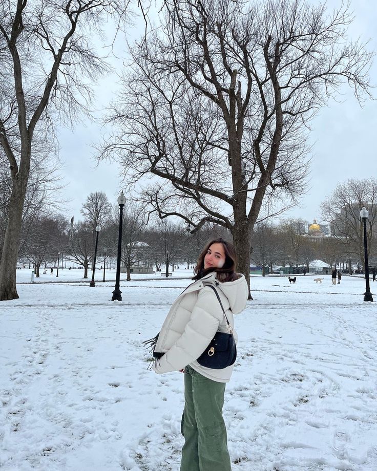 a woman is standing in the snow with her hand up to her face and looking up into the sky