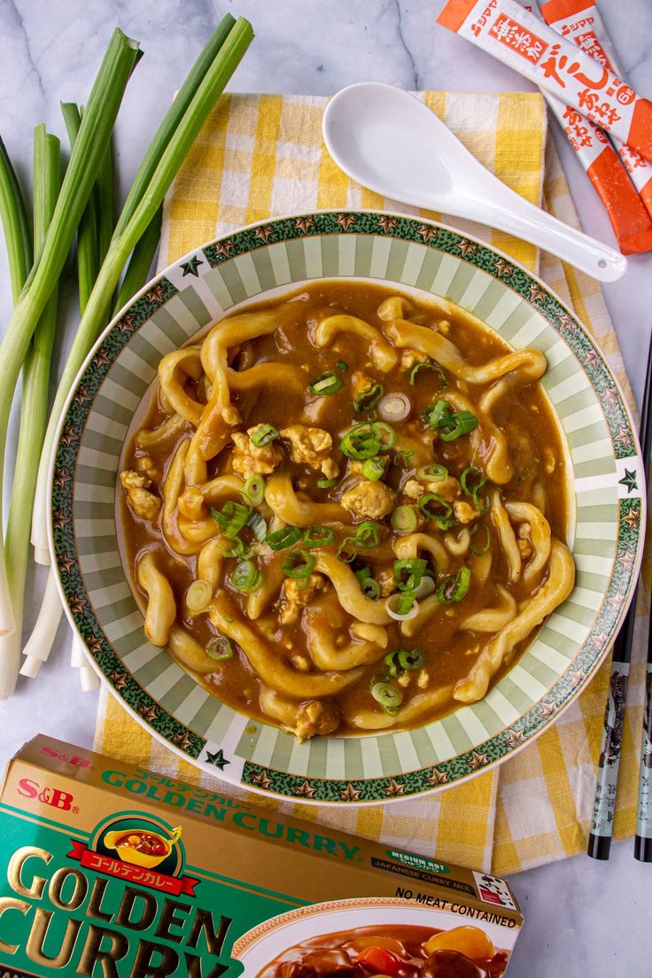 a bowl filled with noodles and vegetables on top of a table next to some chopsticks