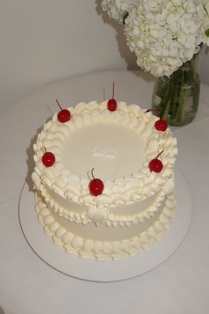 a white cake sitting on top of a table next to a vase filled with flowers