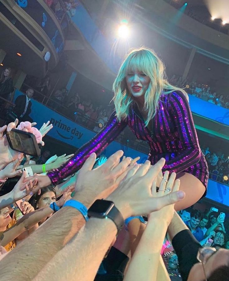 taylor swift is surrounded by fans at a concert in the middle of her performance on stage