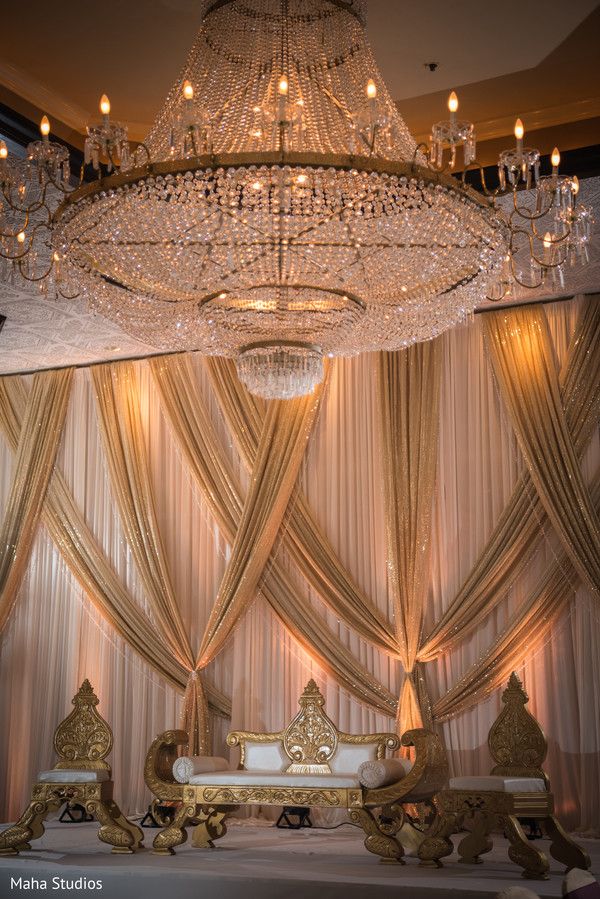 an elaborate chandelier hangs from the ceiling in front of a bed and couch