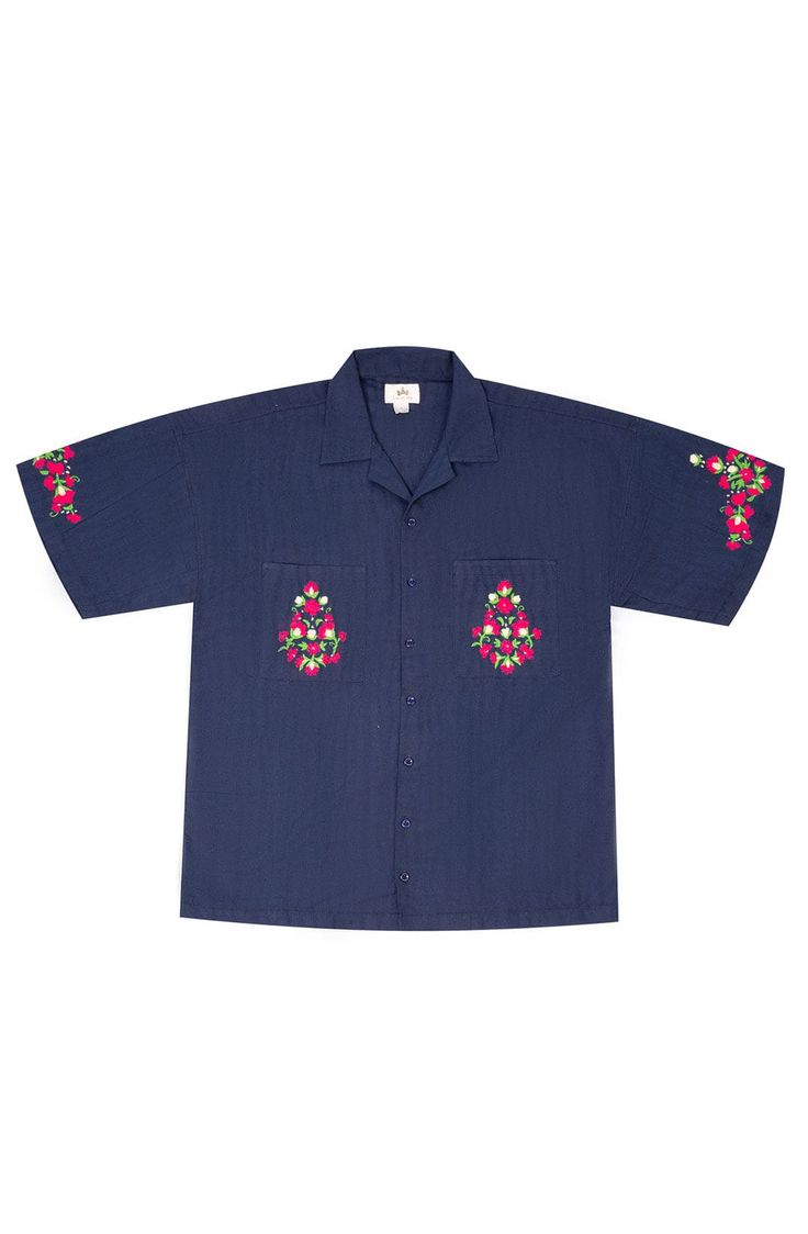 A dark blue cotton embroidered shirt featuring vibrant, plant-inspired embroidery reminiscent of A.R. Chughtai’s art on pockets and sleeves. Relaxed Fit Cotton Camp Shirt With Floral Embroidery, Blue Cotton Shirt With Floral Embroidery, Indigo Cotton Top With Floral Embroidery, Indigo Cotton Tops With Floral Embroidery, Blue Shirt With Floral Embroidery And Relaxed Fit, Blue Floral Embroidered Shirt With Relaxed Fit, Blue Floral Embroidery Shirt With Relaxed Fit, Navy Embroidered Cotton Tops, Blue Embroidered Short Sleeve Shirt