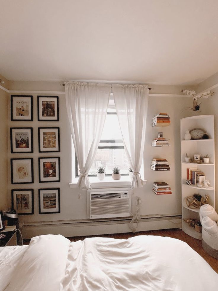 a white bed sitting in a bedroom next to a window with pictures on the wall