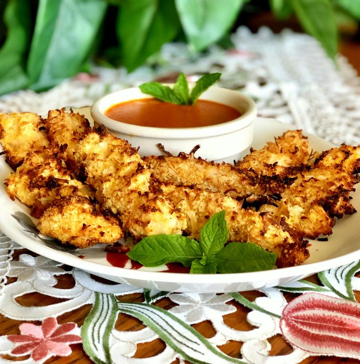 some fried food is on a white plate with sauce and green leafy garnish