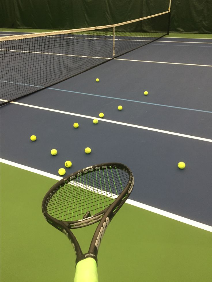 a tennis racket is on the court with yellow balls in the air behind it