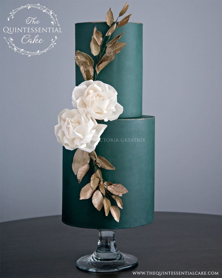 a three tiered green cake with white flowers on the top and leaves on the bottom