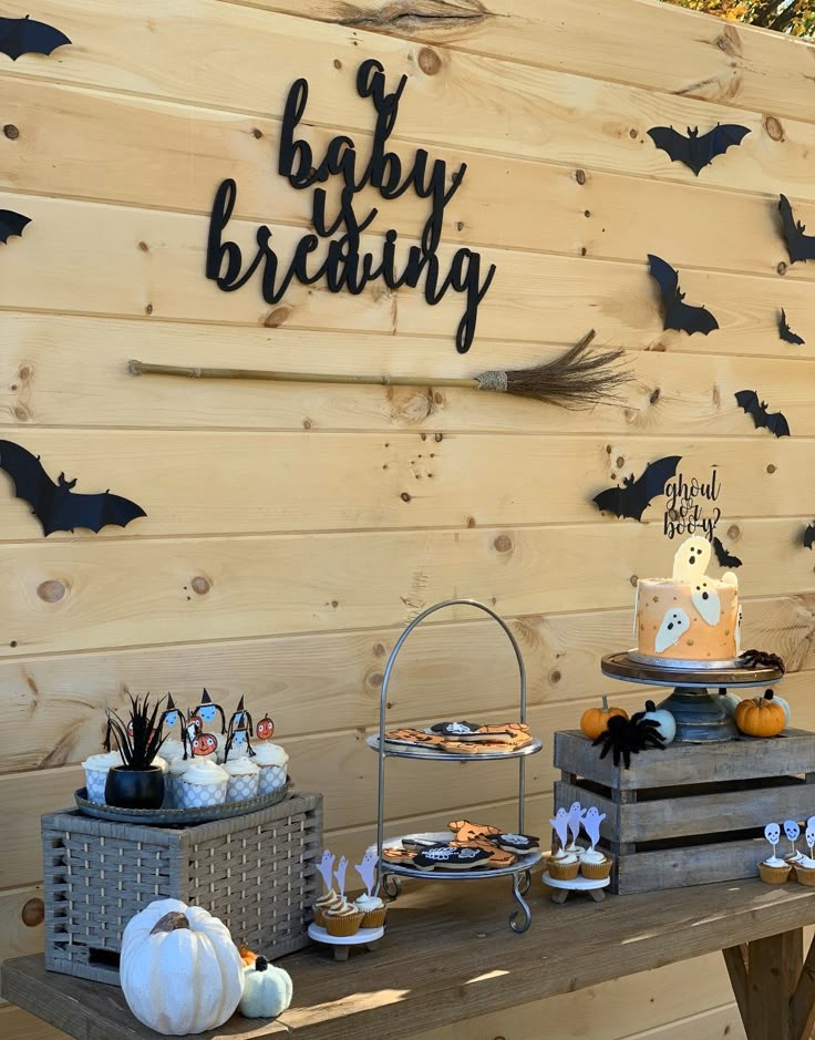 a wooden table topped with lots of desserts next to a wall covered in bats