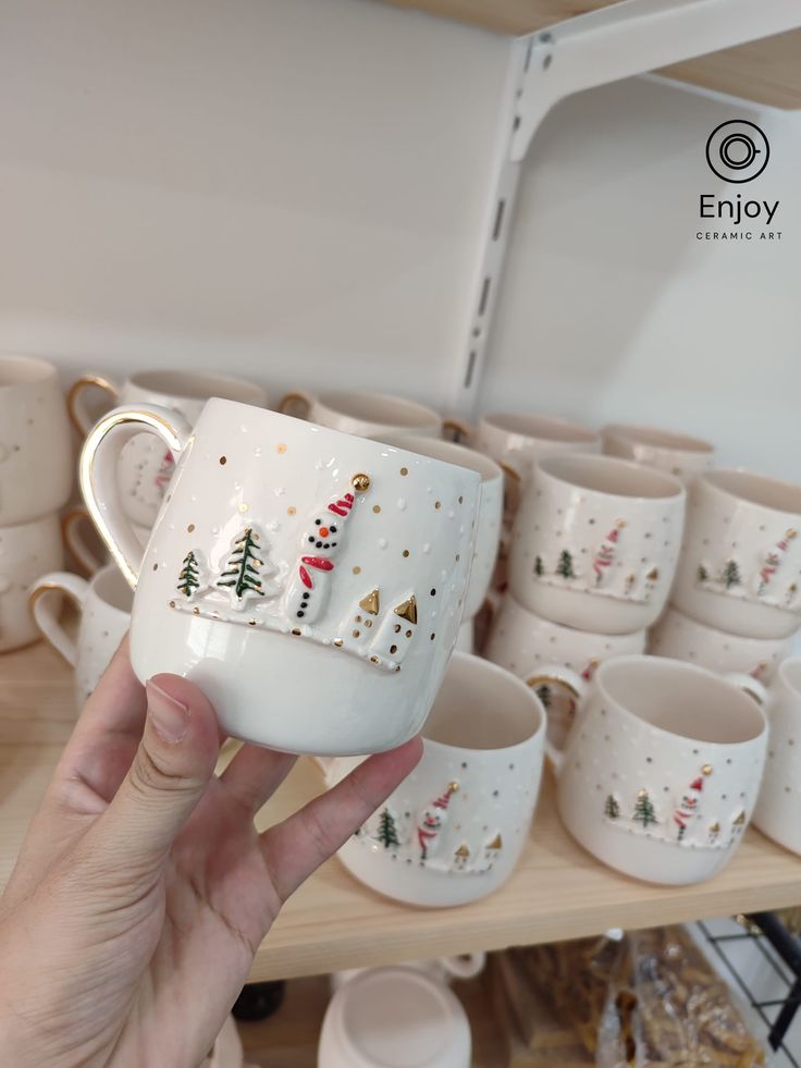 a person holding up a coffee cup with christmas trees on it