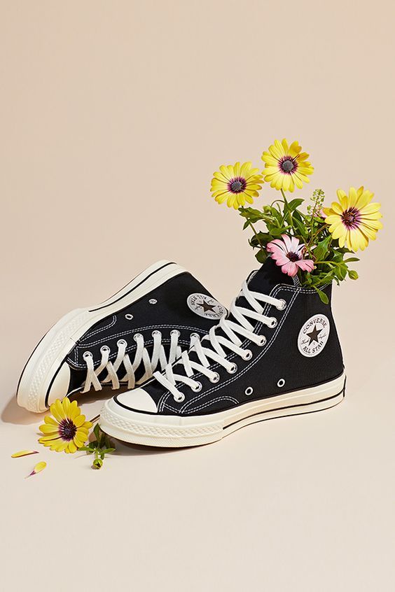 a pair of black sneakers with flowers in them