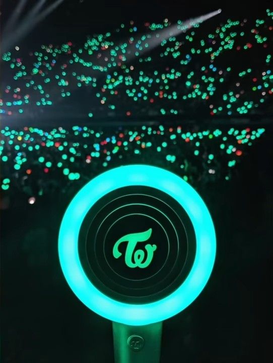 a green and blue light up device in the dark with fireworks coming out behind it