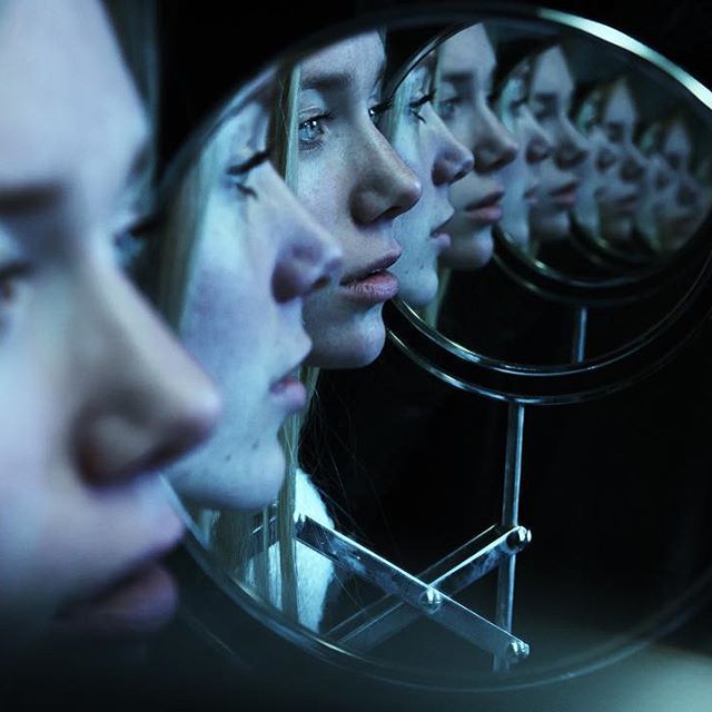 a woman's reflection in a mirror with her face close to the camera as she looks at herself