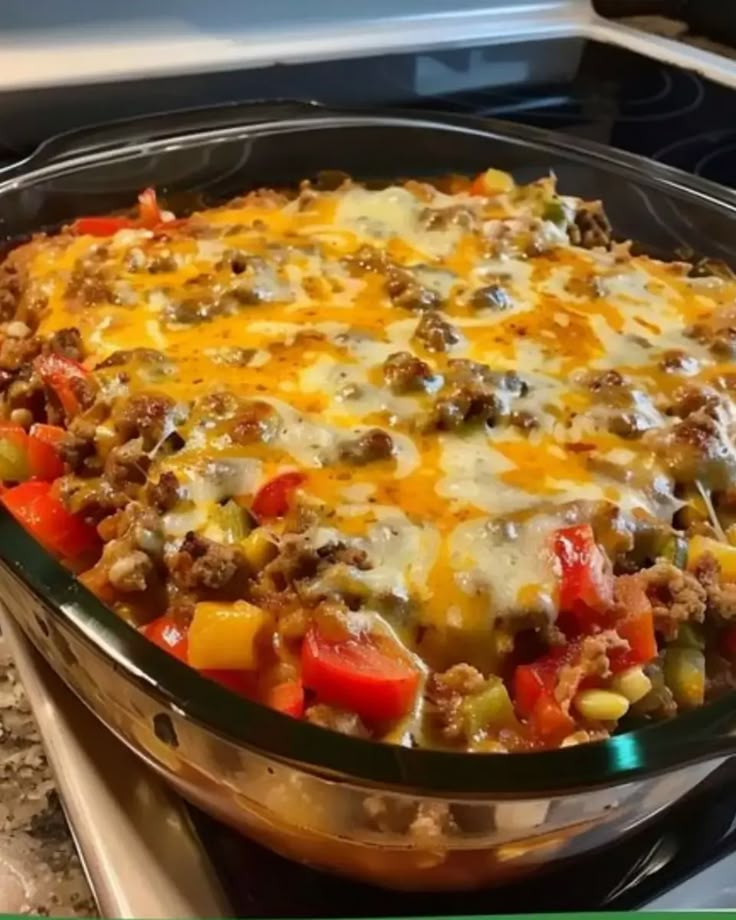 a casserole dish with meat, vegetables and cheese in it on the stove