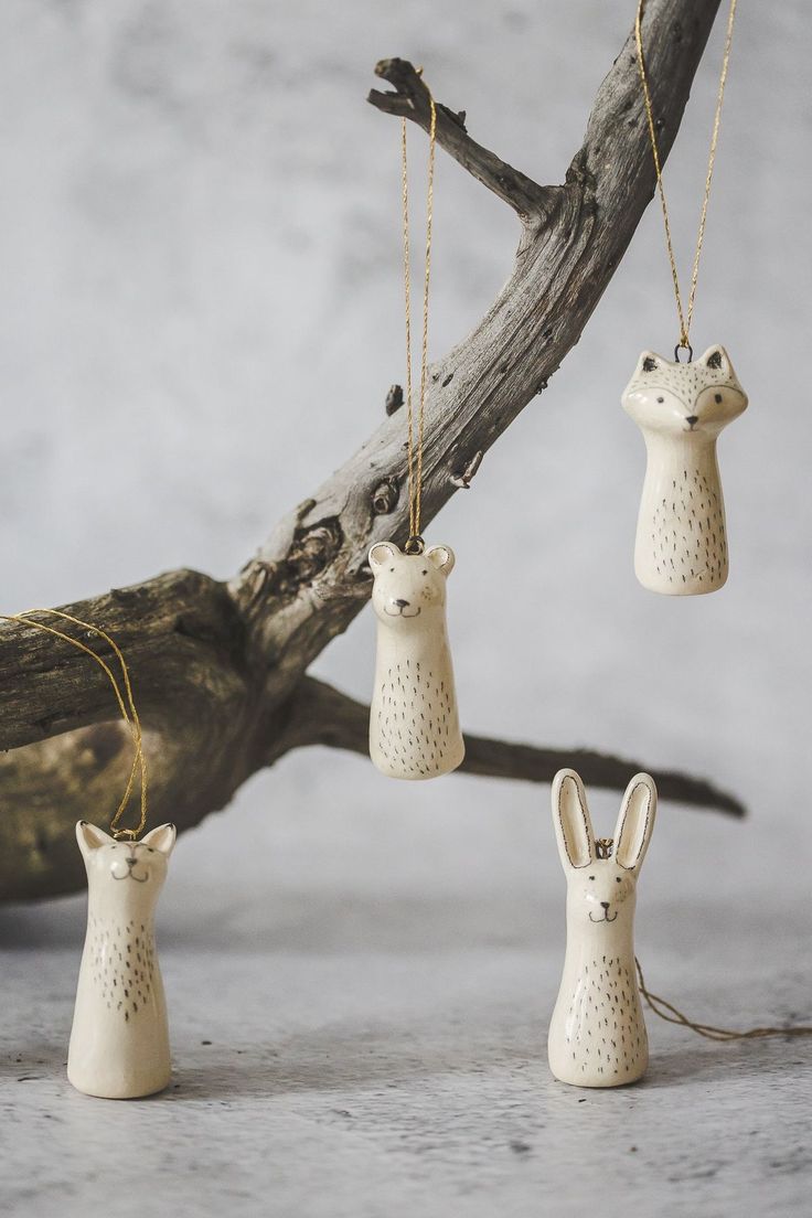 three ceramic rabbits hanging from chains on a branch