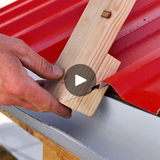 a person is using a piece of wood to attach the top of a red roof