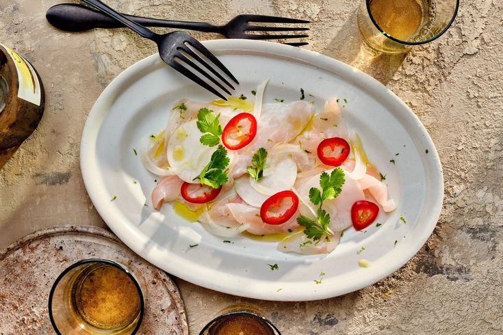 a white plate topped with shrimp and veggies next to two glasses of beer