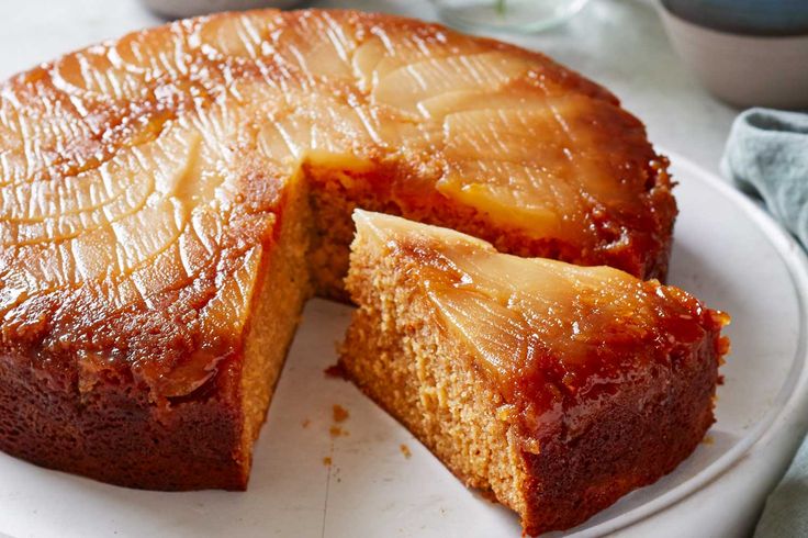 a pineapple upside down cake on a white plate with one slice cut out and ready to be eaten