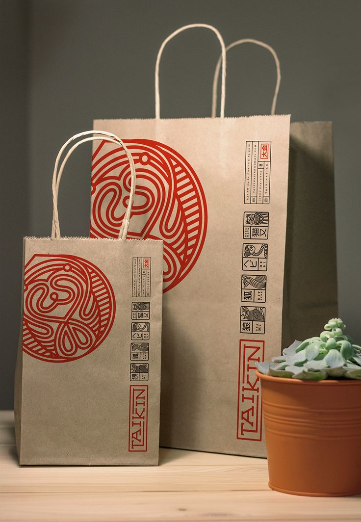 two brown bags sitting on top of a wooden table next to a potted plant