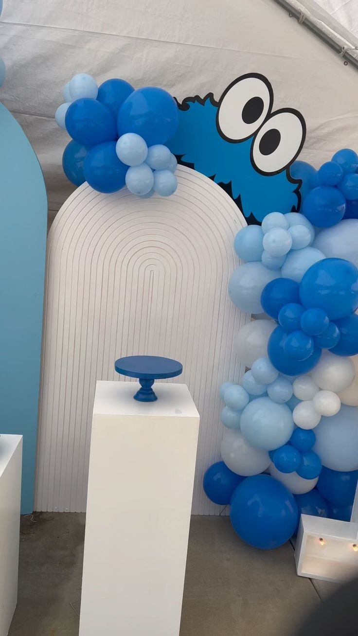 blue and white balloons are on display in front of a wall with an image of cookie monster