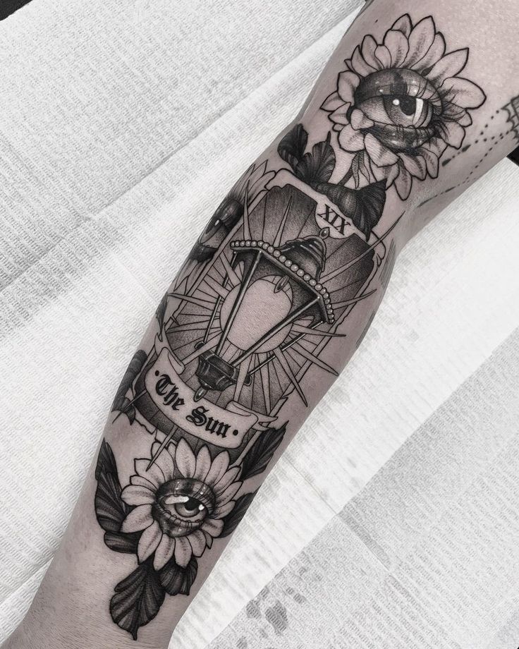 a person with a tattoo on their arm that has flowers and a hot air balloon