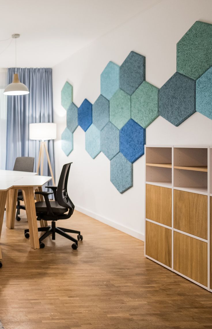 an office with wood flooring and white walls decorated with hexagonal tiles on the wall