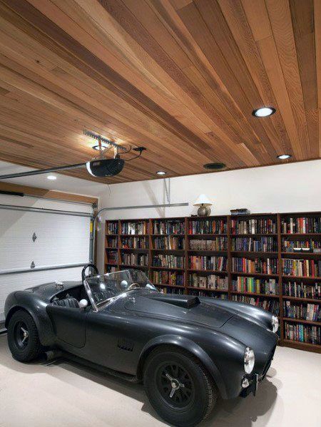 an antique sports car is parked in front of a bookshelf