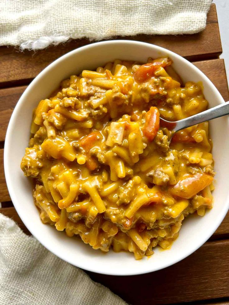 a white bowl filled with macaroni and cheese on top of a wooden table