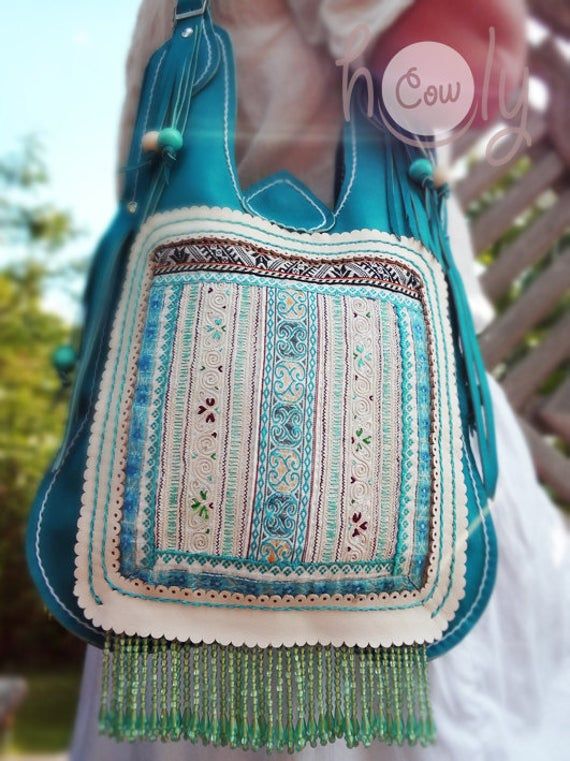 Totally unique one off 100% handmade funky turquoise leather Hmong shoulder bag. This leather bag is made from beautiful turquoise leather and is fantastically designed. The bag has beautiful Hmong hill tribe vintage fabric on the front of it. The hand embroidery is simply amazing. There are also hand painted wooden balls attached to the sides of the bag and beautiful turquoise beads attached to the bottom of the bag. The is closed by a magnetic clip. The bag has a main compartment with a small Turquoise Pouch Shoulder Bag For Travel, Bohemian Turquoise Bags For Festival, Bohemian Turquoise Travel Bag, Turquoise Everyday Pouch Shoulder Bag, Bohemian Turquoise Shoulder Bag, Turquoise Bags For Festivals, Turquoise Bohemian Shoulder Bag, Handmade Blue Bohemian Hobo Bag, Handmade Blue Hobo Shoulder Bag