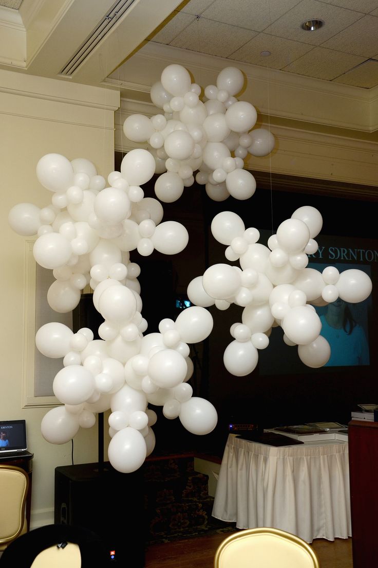 a bunch of white balloons are floating in the air over chairs and table cloths