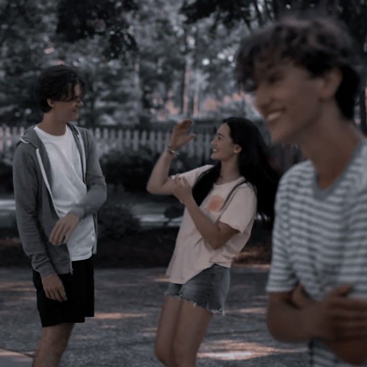 three young people standing around talking and laughing