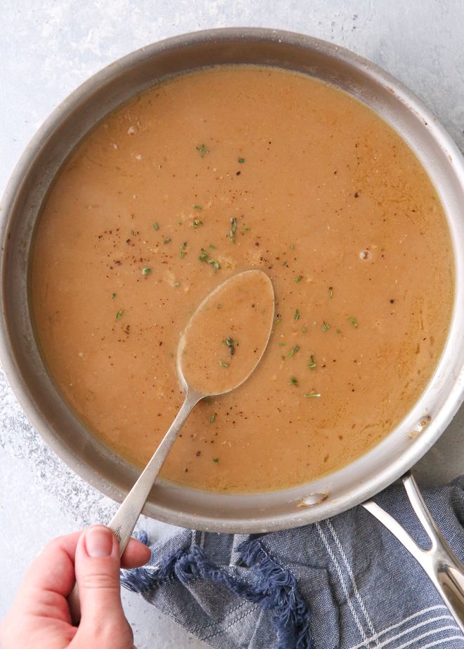 a person holding a spoon over a bowl of soup