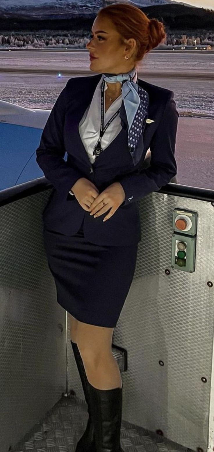 a woman in a suit and boots is sitting on an airplane deck with her legs crossed